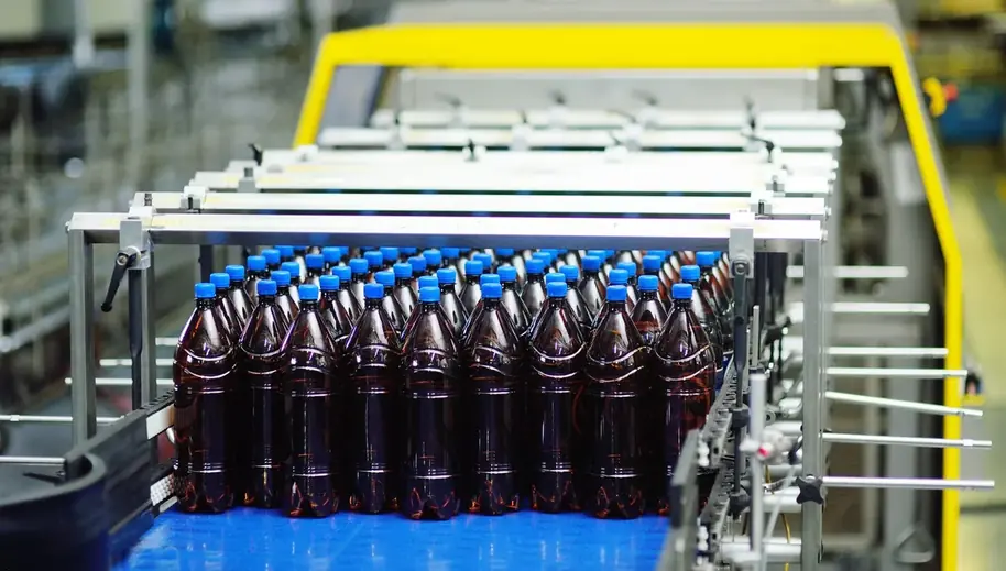 Linha de envase com garrafas percorrendo a esteira