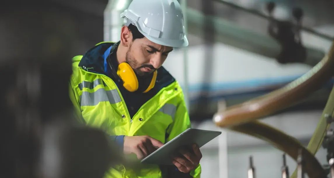 Operador com equipamento de proteção usando tablet na indústria